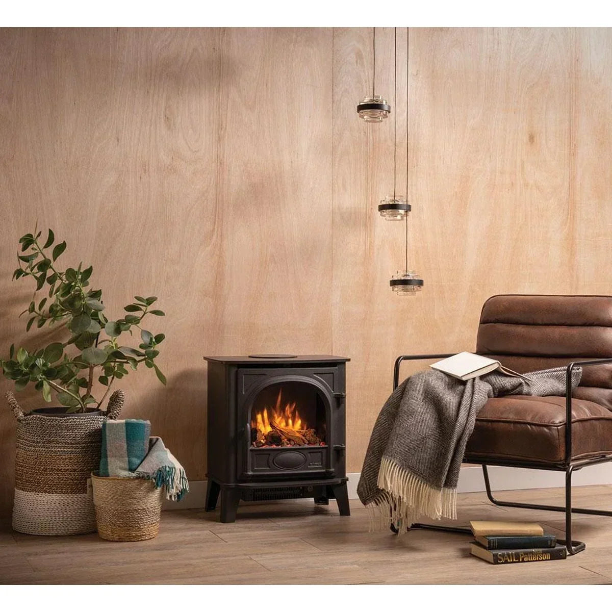 Electric stove heater with flame effect beside a brown armchair and potted plant