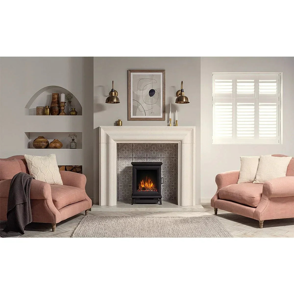 Blush pink fabric armchairs in living room with fireplace and grey patterned rug