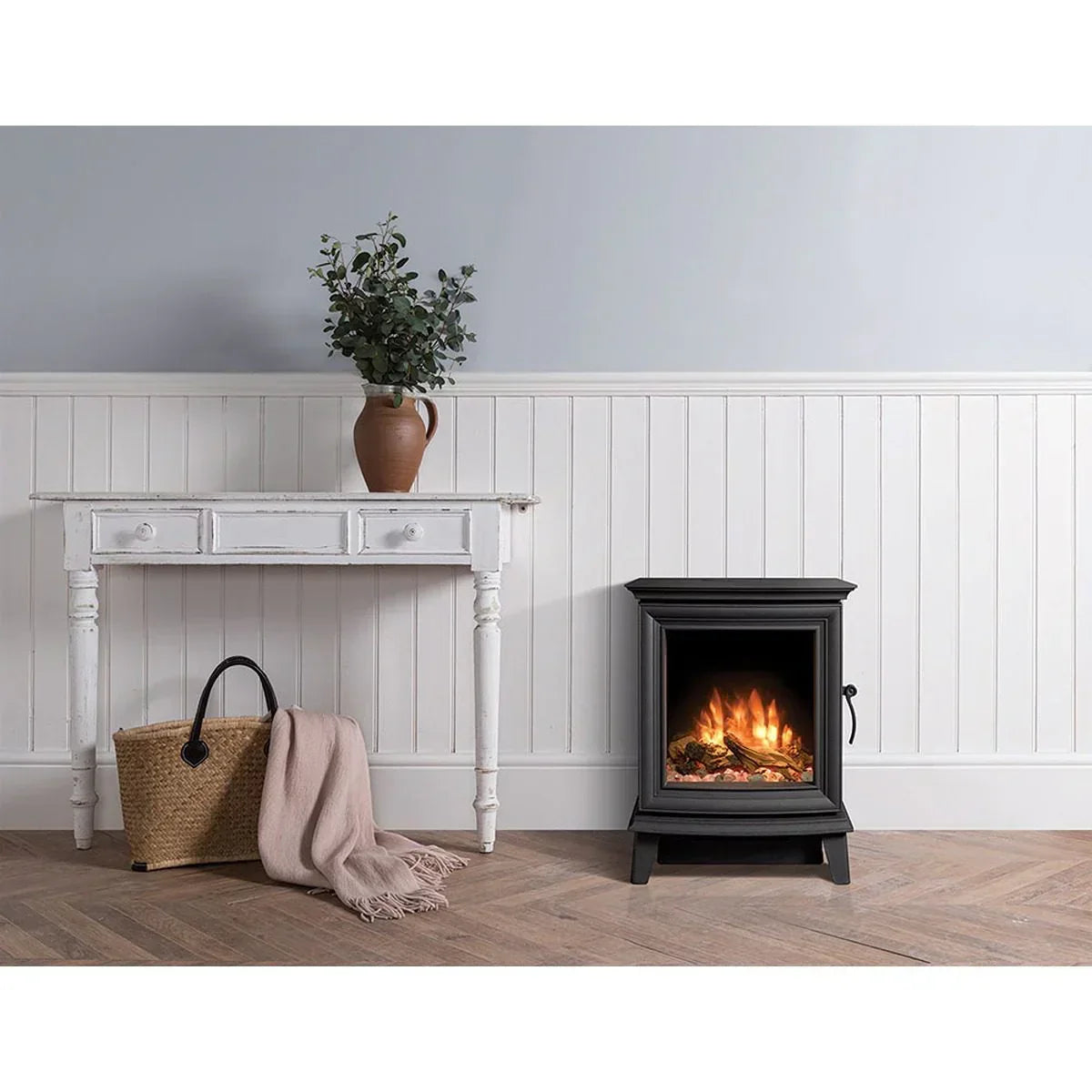 Black electric stove heater with realistic flame beside white console table in living room