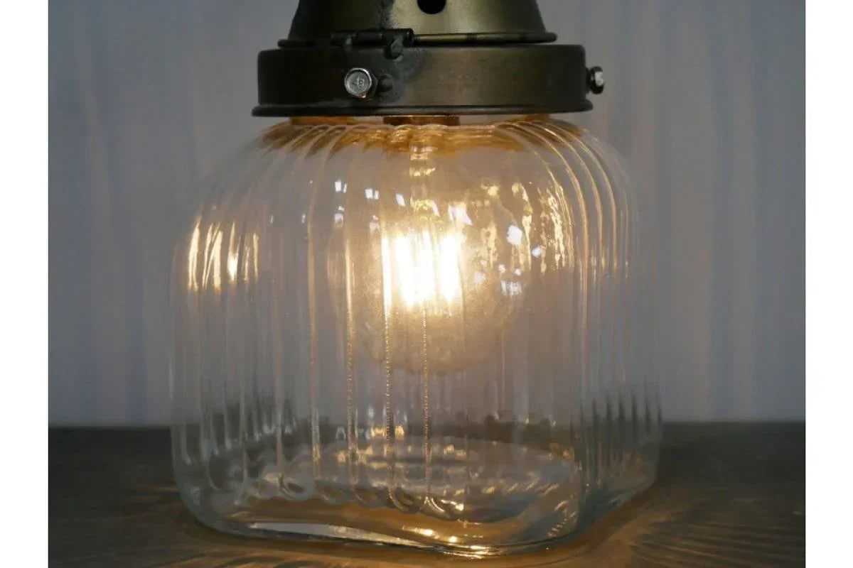 Glass pendant light with ribbed shade and warm glowing bulb