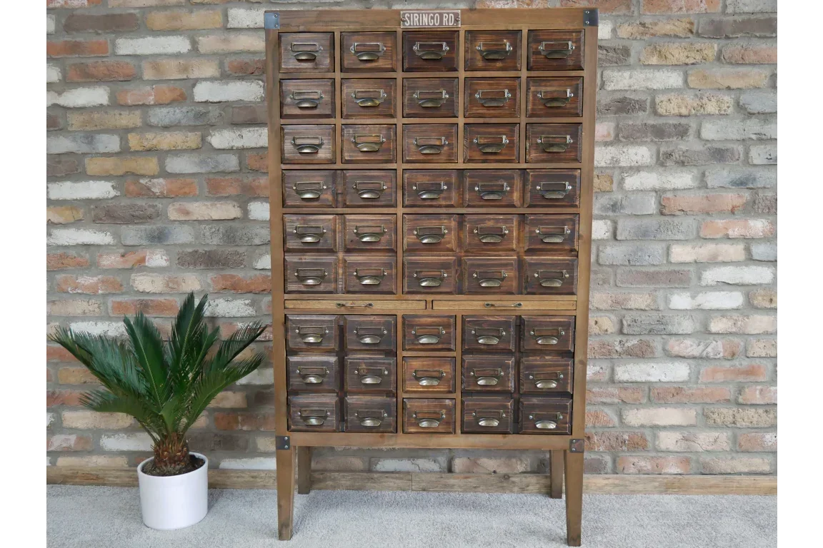 Vintage multi-drawer wooden storage cabinet with brass handles against brick wall