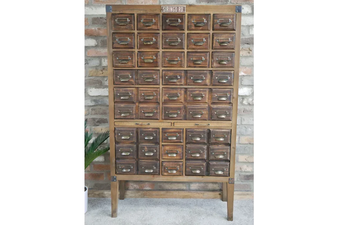 Vintage wooden multi-drawer storage cabinet with metal handles against brick wall