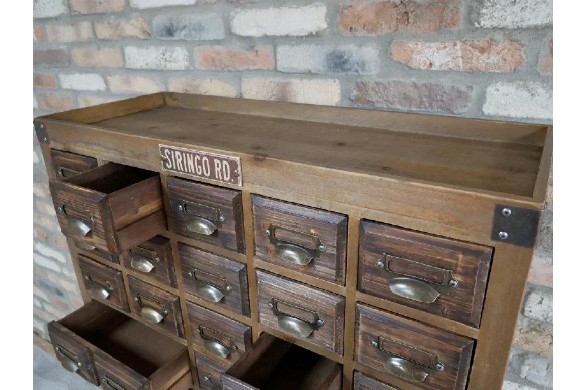 Wooden storage cabinet with multiple drawers and metal handles against brick wall