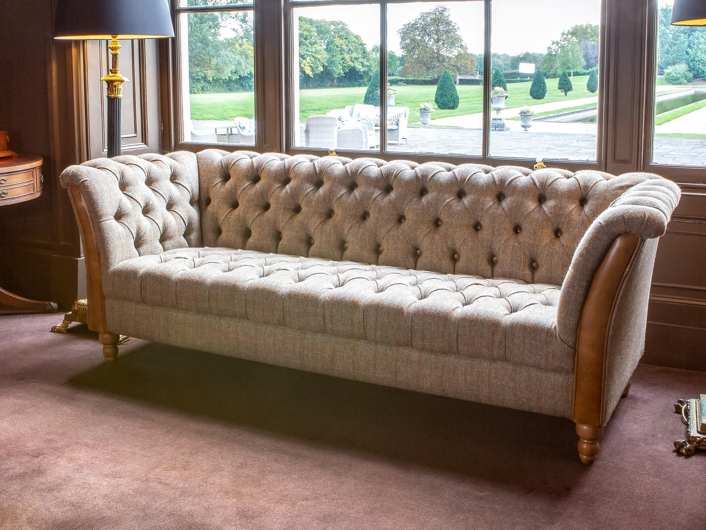 Button-tufted fabric sofa with rolled arms and wooden legs in traditional living room