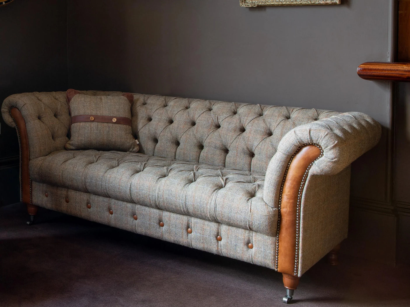 Tufted tweed chesterfield sofa with brown leather accents and button details in living room