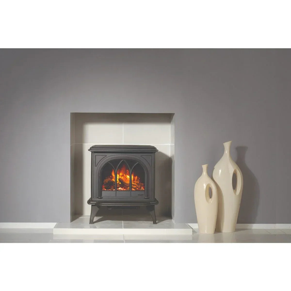 Black electric stove heater with realistic flames beside two cream decorative vases on tiled floor