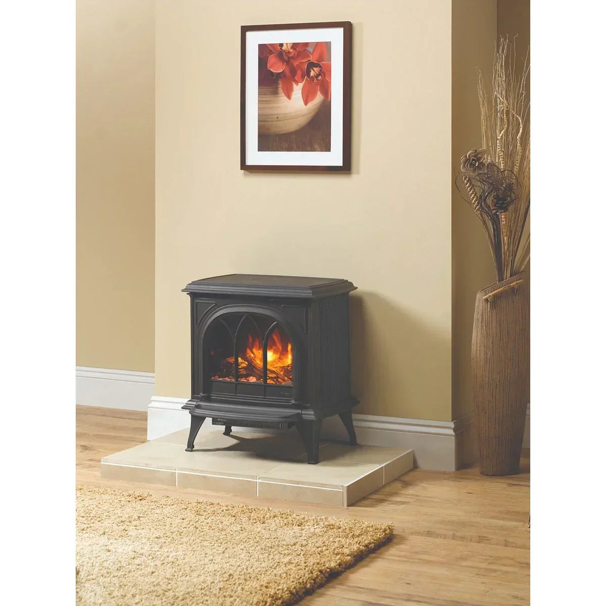 Black electric stove heater with flame effect on hearth, beige wall, floral framed print above