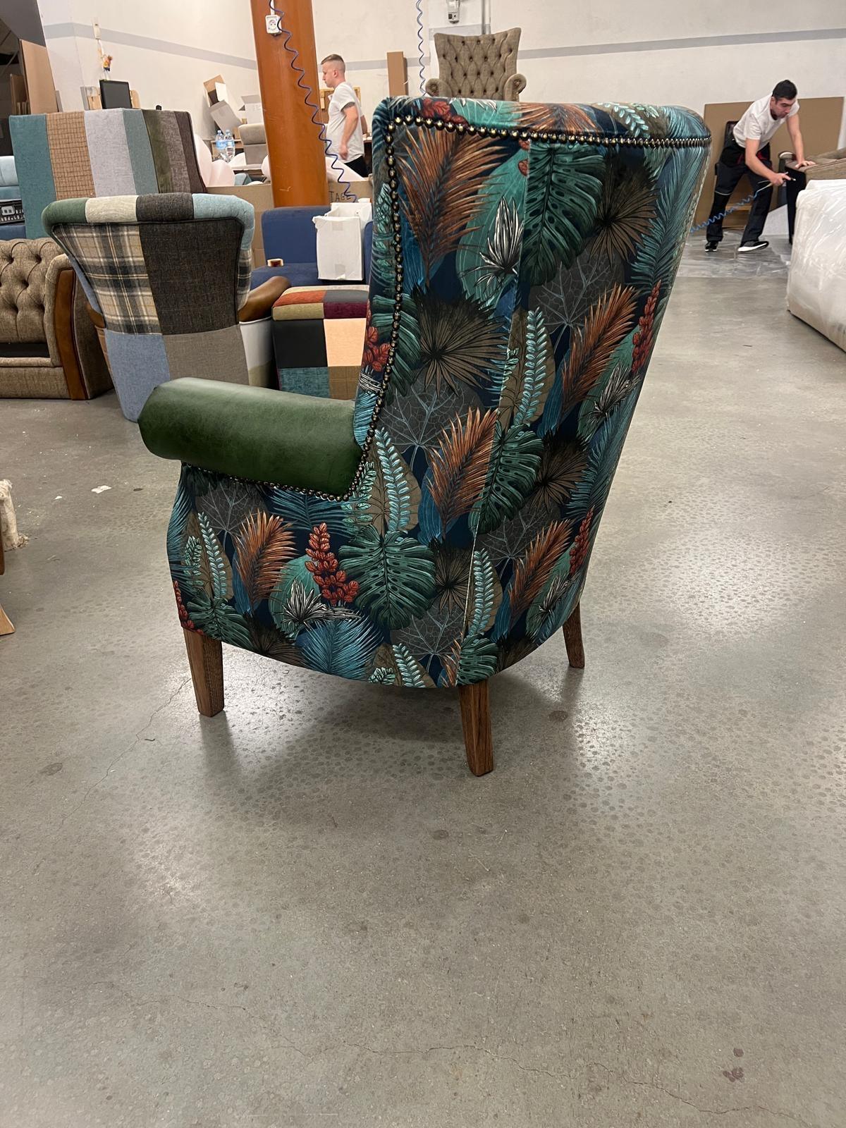 Floral wingback armchair with green velvet armrest and wooden legs on showroom floor