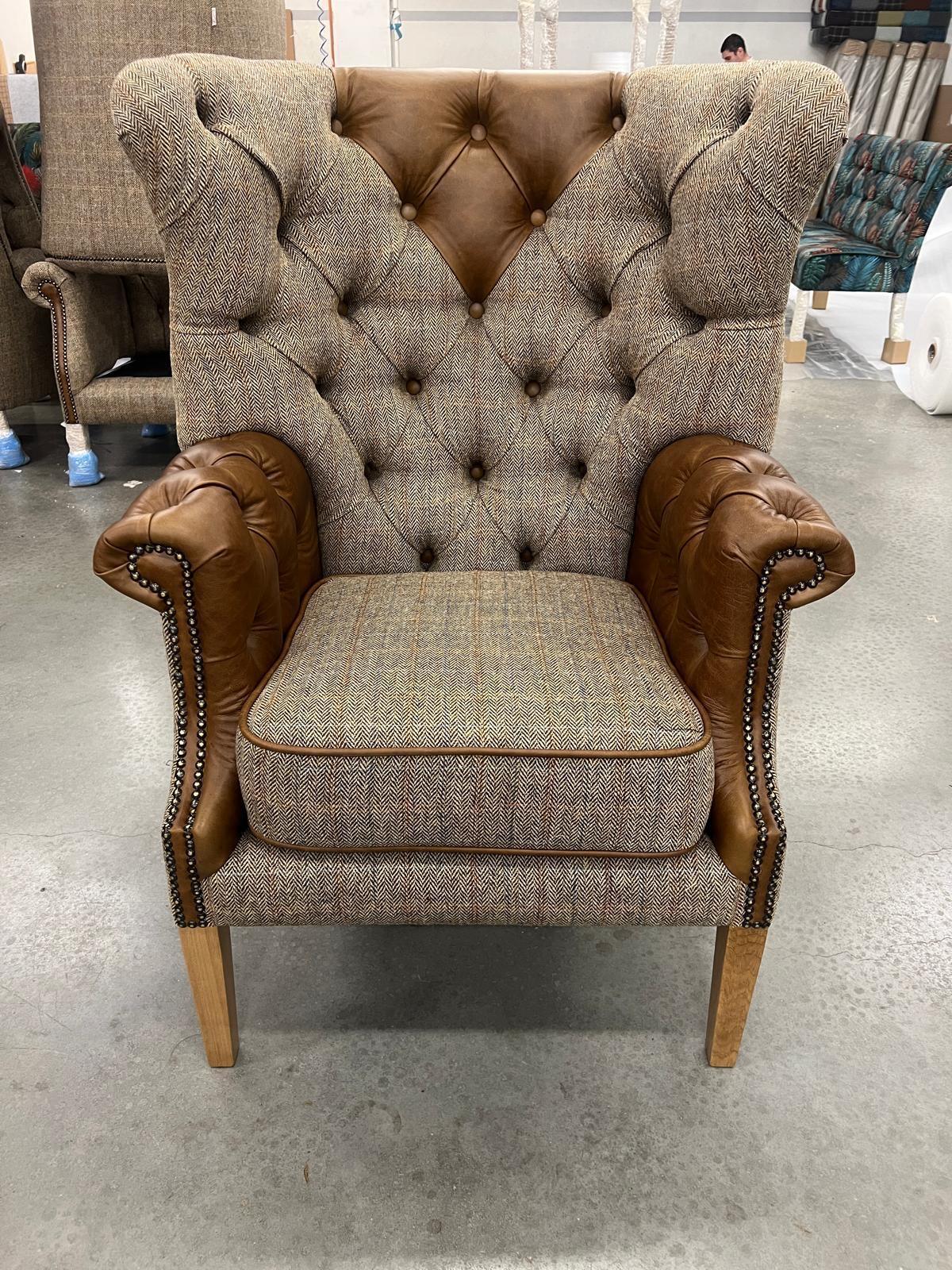 Button-tufted high back armchair with brown leather arms and herringbone fabric upholstery
