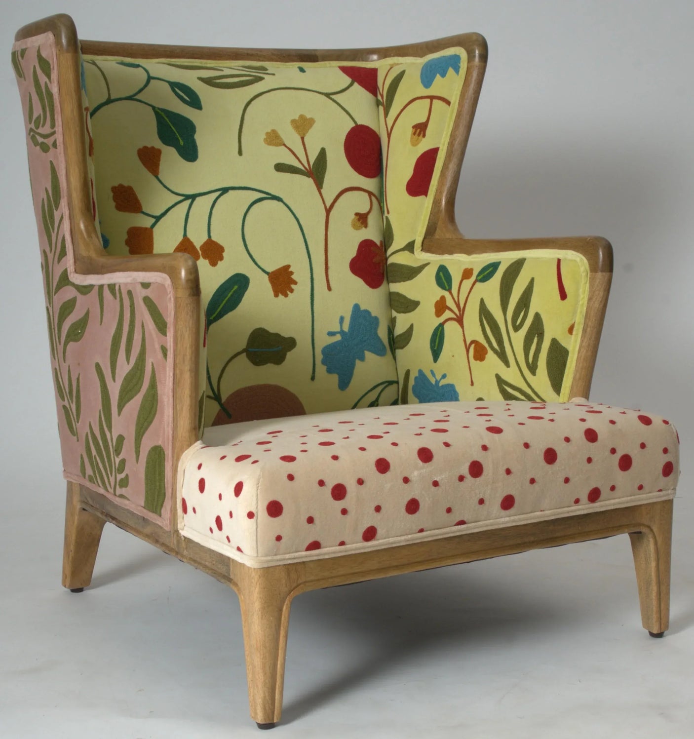 Wingback armchair with wooden frame, floral patterned fabric and red polka dot seat