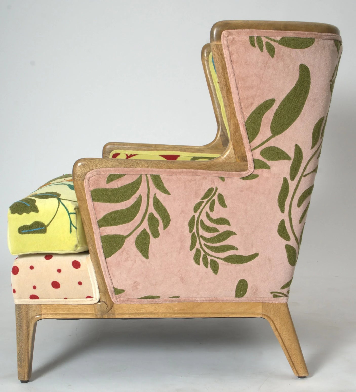 Patterned accent chair with pink and green leaf upholstery, wooden frame, side view