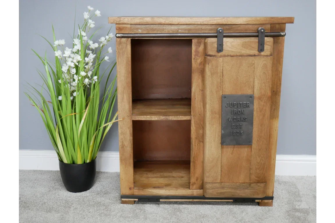 Rustic wooden sideboard with sliding barn door and metal plaque, beside green plant pot