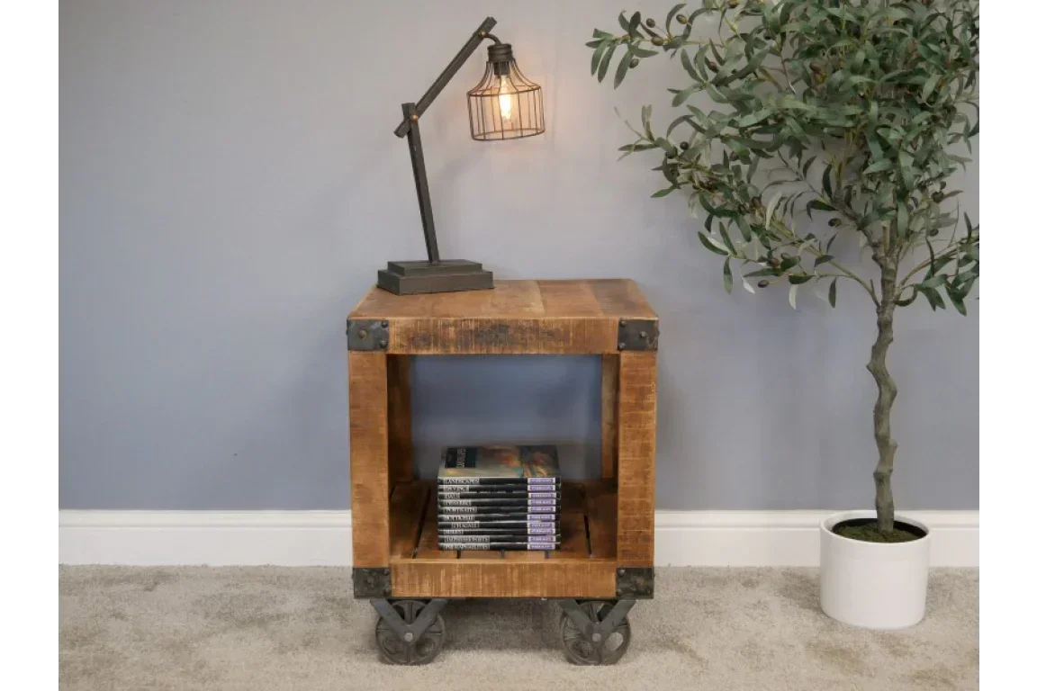 Industrial wood side table with metal wheels, shelf storage, lamp, and potted plant