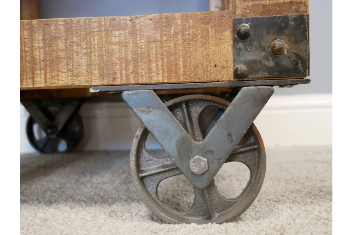 Industrial coffee table cast iron wheel and wood corner detail on carpet