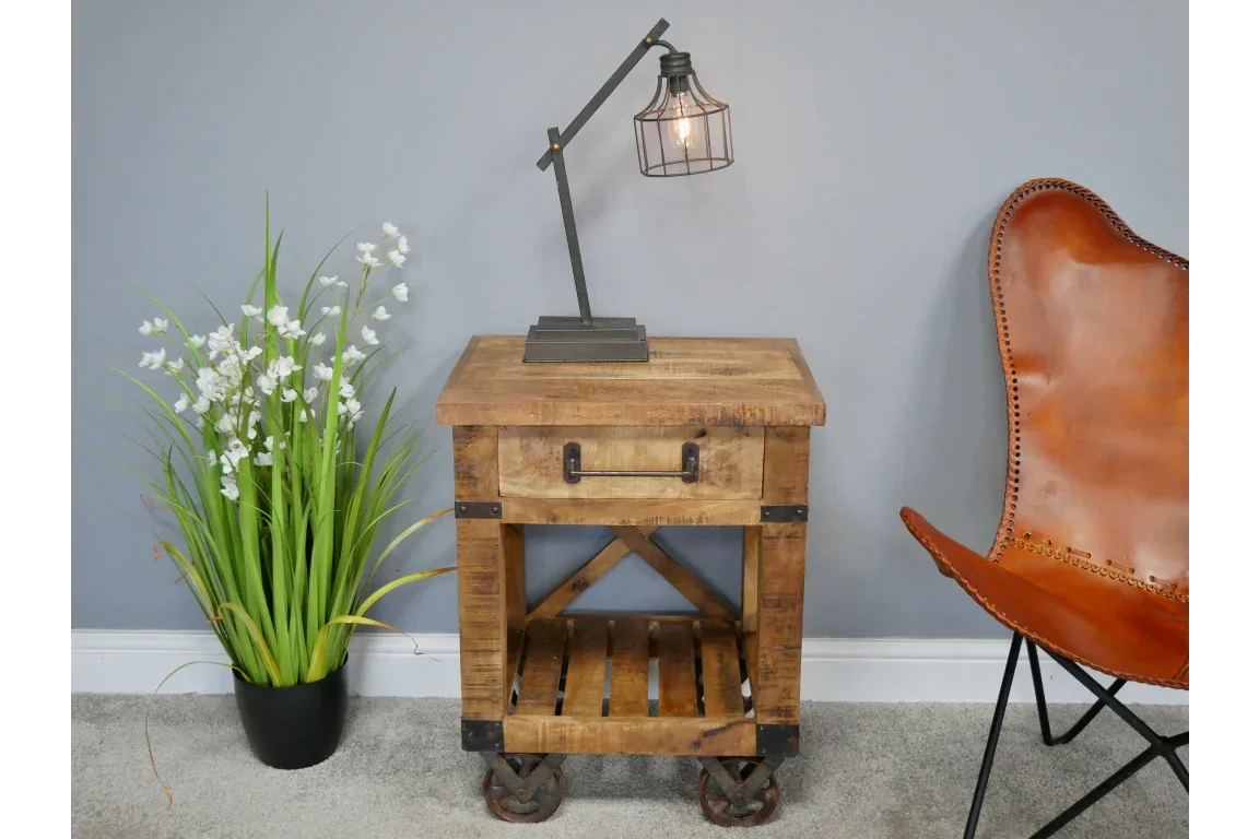 Rustic wooden bedside table with drawer and shelf, industrial lamp on top, staged in room