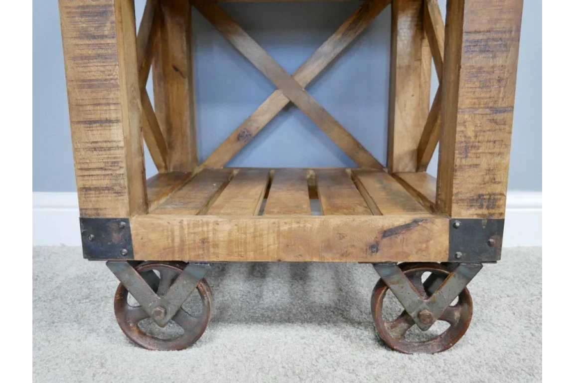 Rustic wooden furniture cart with metal wheels and slatted shelf on carpet