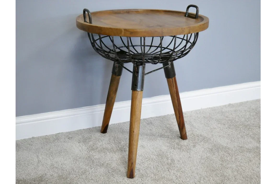 Round wooden side table with metal wire basket base and tripod legs on carpet