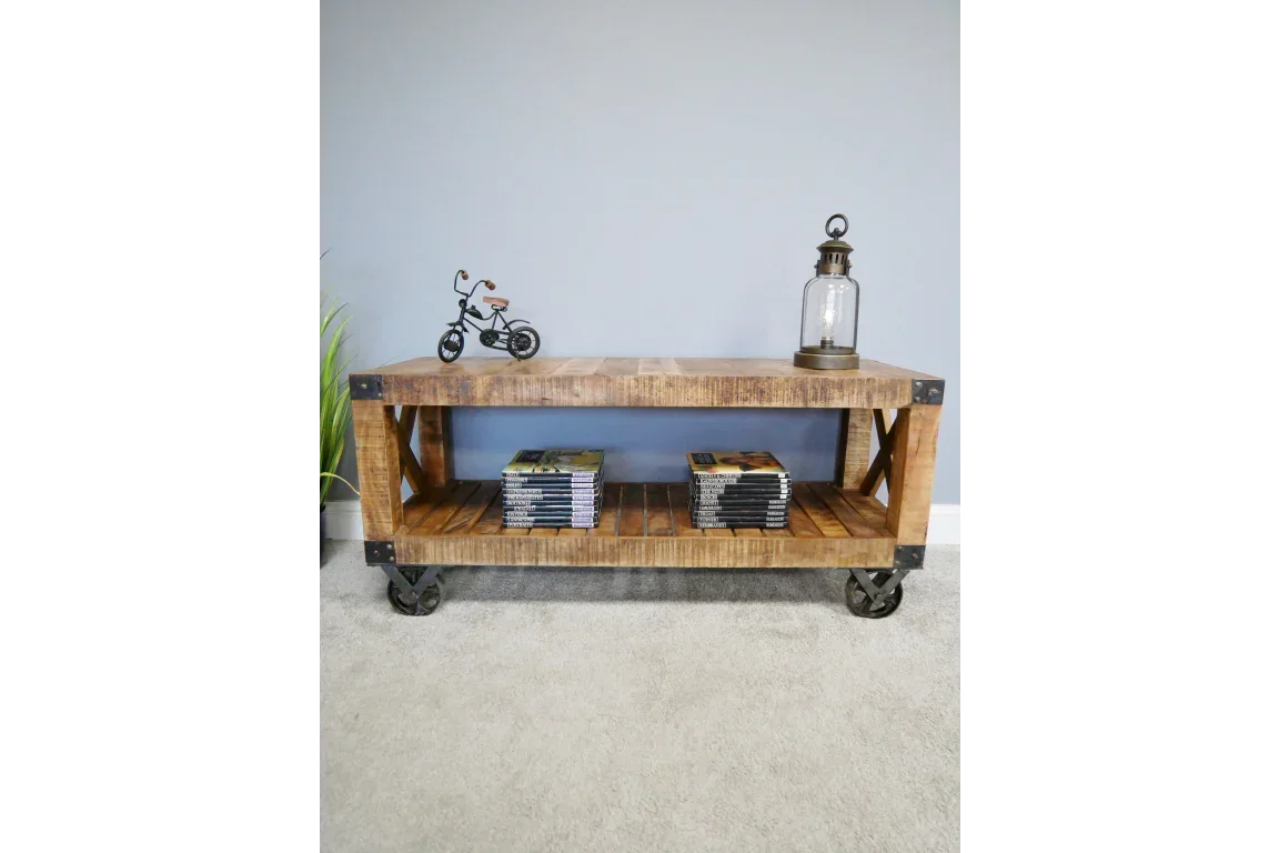 Industrial wooden coffee table with metal wheels and shelf, decorated with lamp and model bike