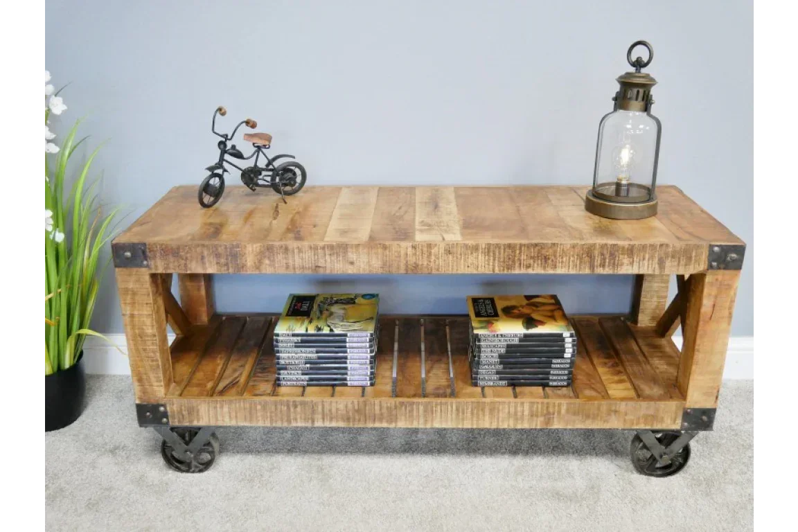 Industrial wood coffee table with metal wheels, shelf below holds books and magazines