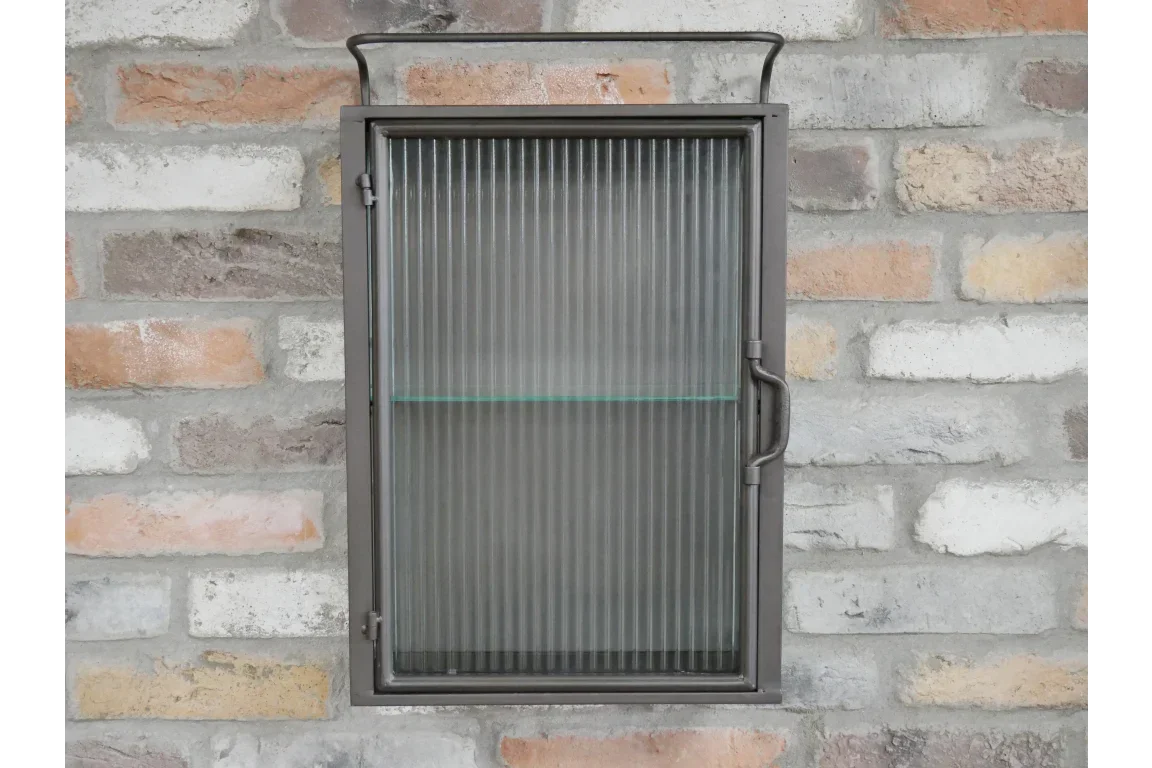 Wall-mounted metal cabinet with ribbed glass door against brick background