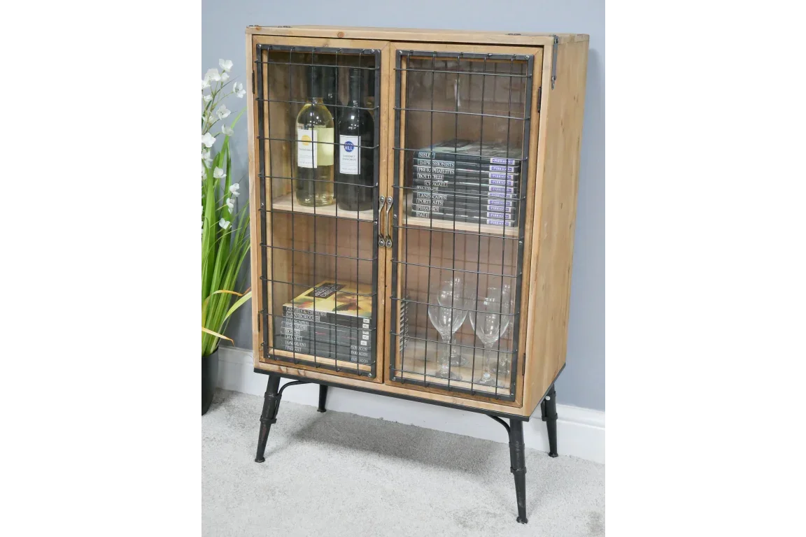 Industrial wood display cabinet with wire doors, shelves holding wine bottles, books, glassware