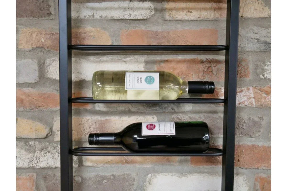 Metal wall wine rack holding two wine bottles against brick background