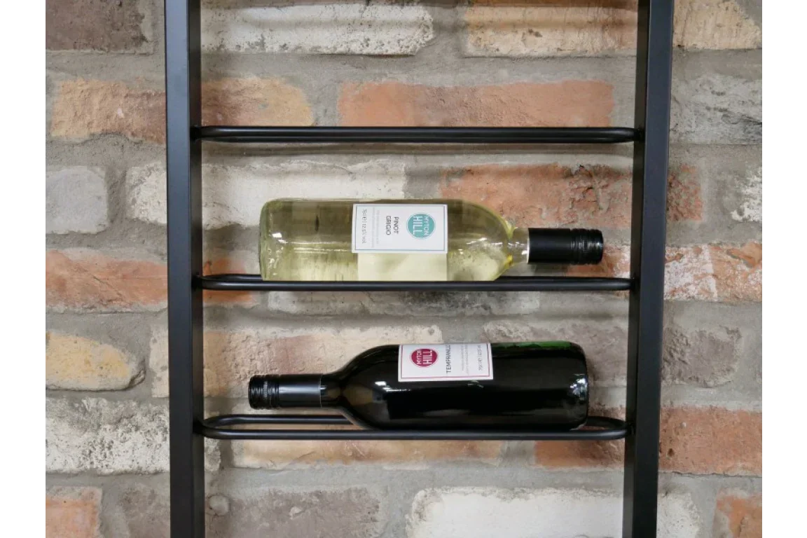 Black metal wall wine rack with two bottles displayed against exposed brick