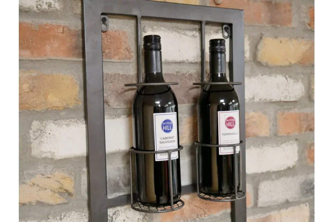 Wall-mounted metal wine rack holding two wine bottles against brick wall