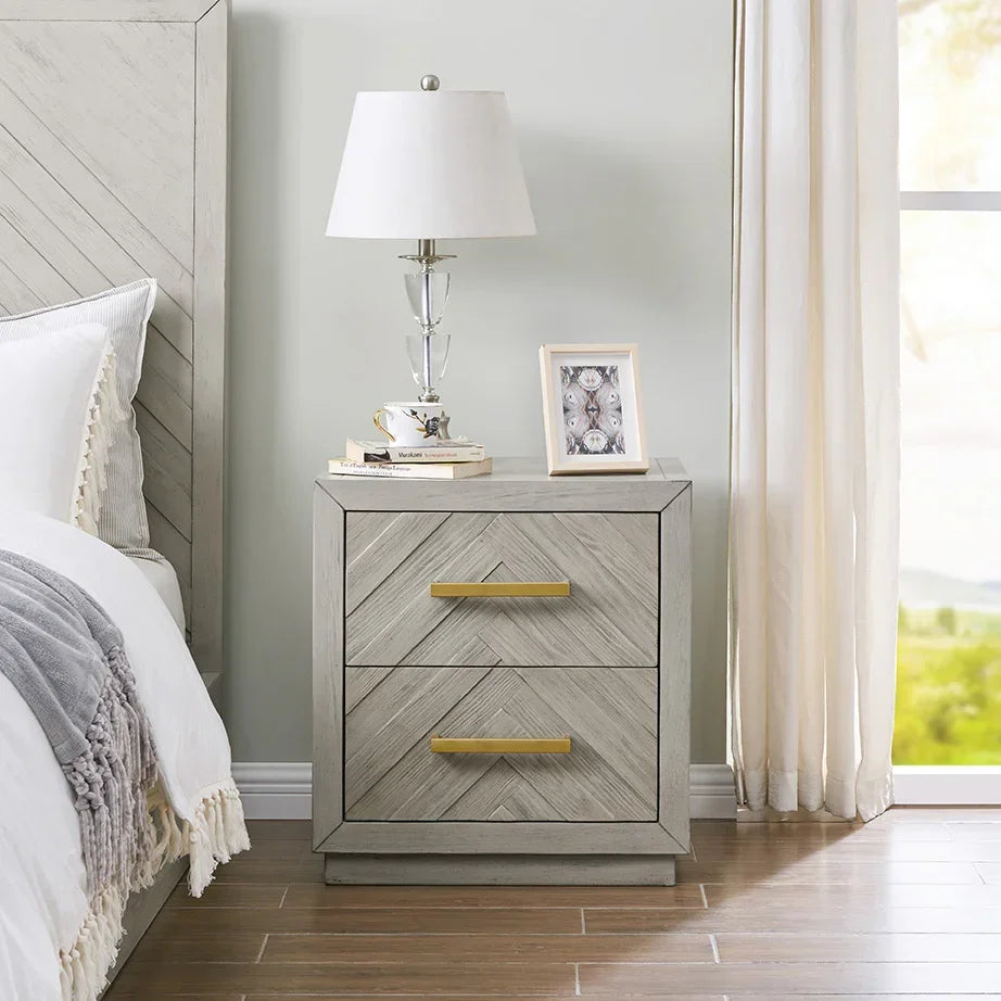 Light wood bedside table with gold handles and two drawers beside bed and window