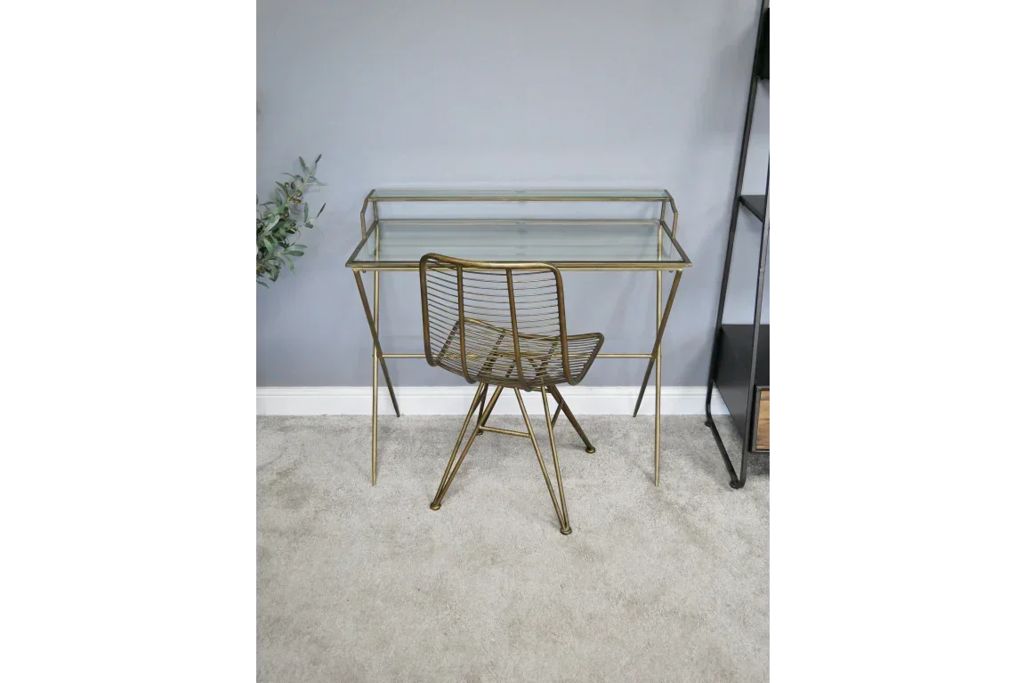 Glass top desk with gold metal frame and matching chair on grey carpet