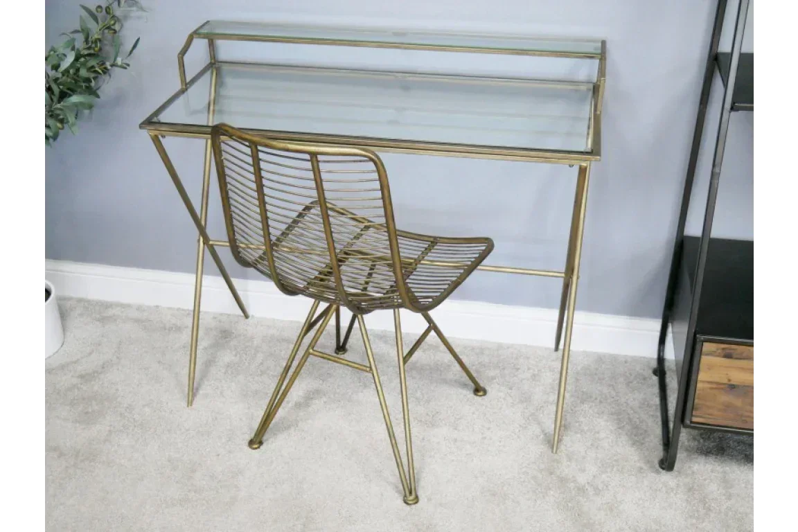 Glass top writing desk with gold metal frame and matching wire chair in home office