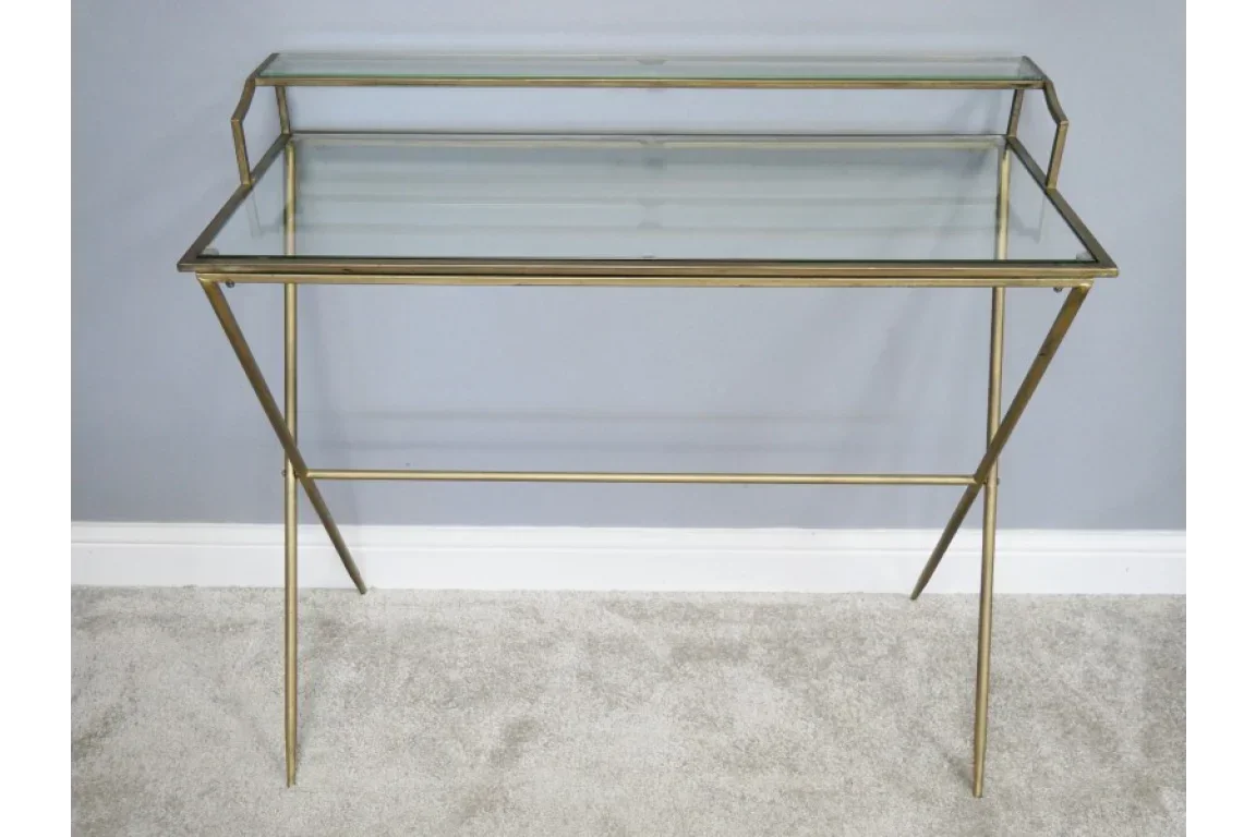 Glass console table with gold metal frame and two shelves against grey wall