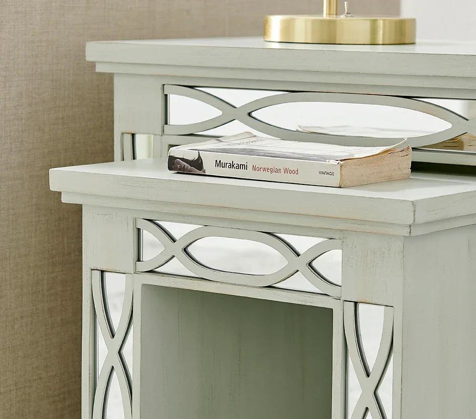 Light grey wooden bedside table with mirrored lattice trim and book on top