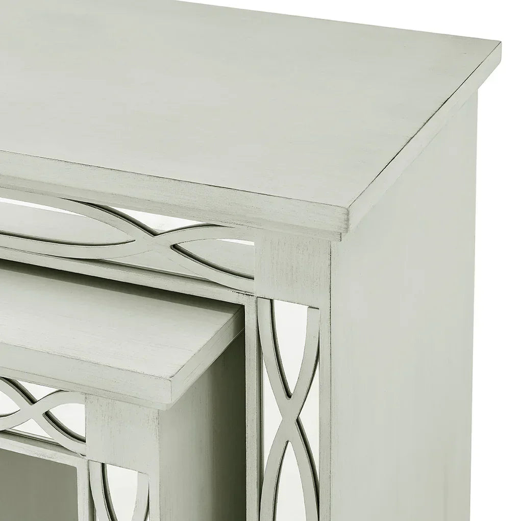 Close-up of silver wooden nesting tables with carved geometric detailing on side panel