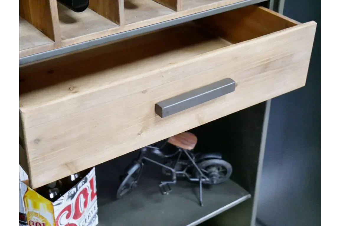 Wooden furniture drawer with metal handle above a shelf displaying decor and bottled drinks