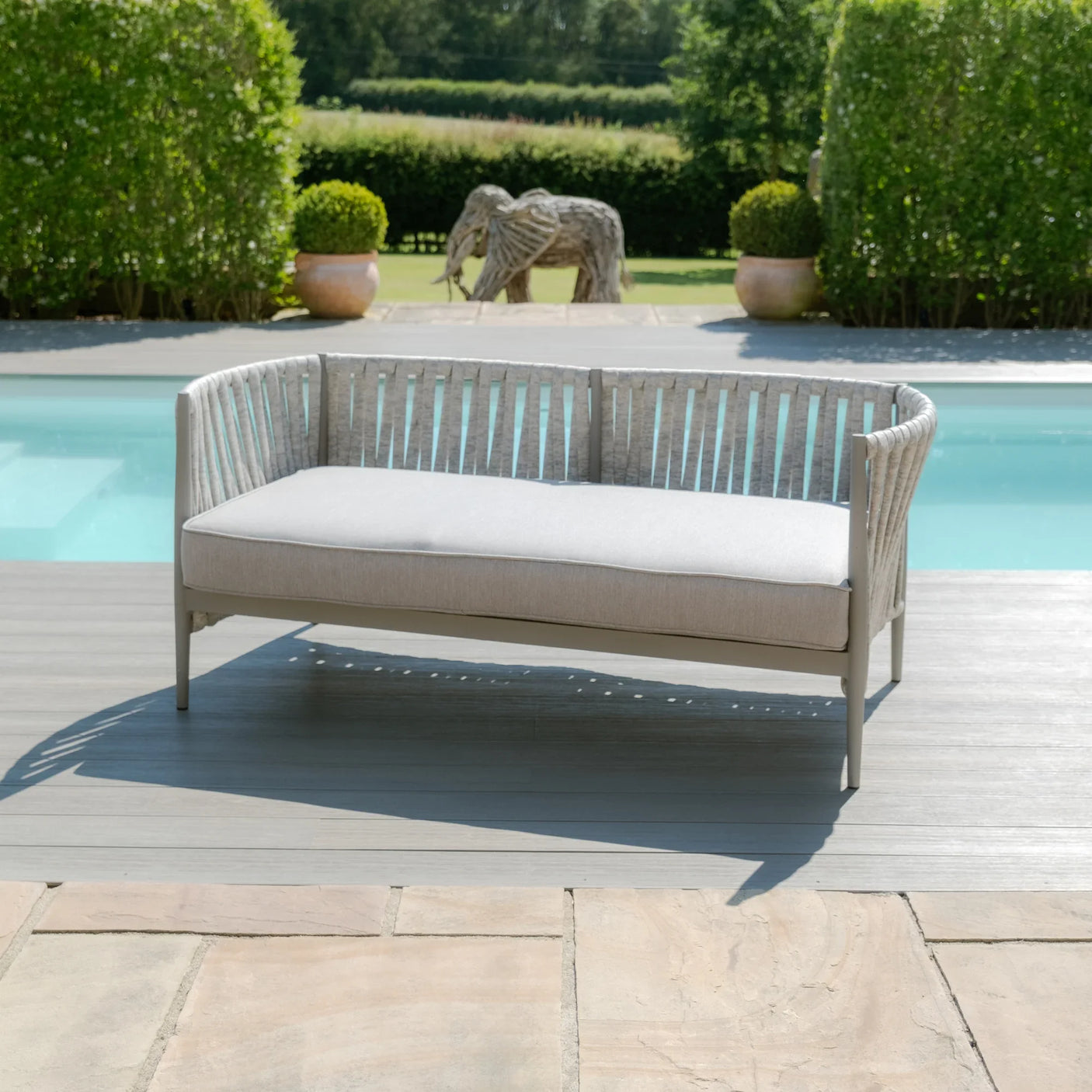 Light grey outdoor sofa with cushions on decking beside swimming pool