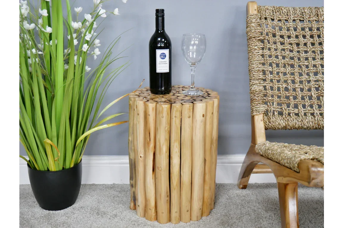 Rustic wooden side table with round top, wine bottle and glass beside woven chair