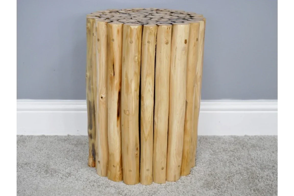 Round wooden side table made from natural log pieces, set on a grey carpeted floor