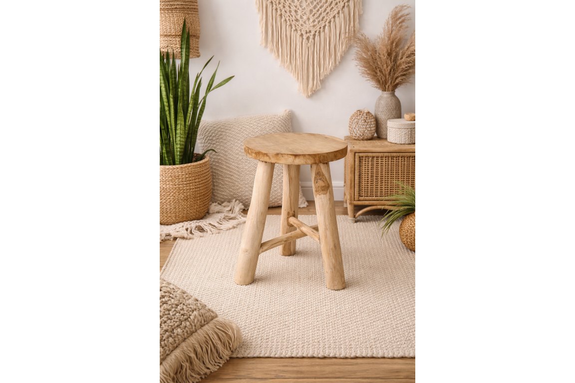 Round wooden stool with three legs in a beige, bohemian-style room setting with plants and woven decor.