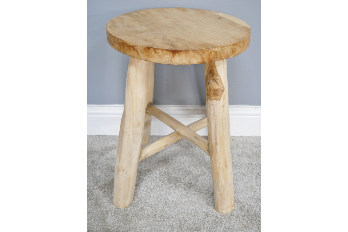 Round wooden stool with three legs and cross support, light natural wood finish, front angle on carpeted floor.