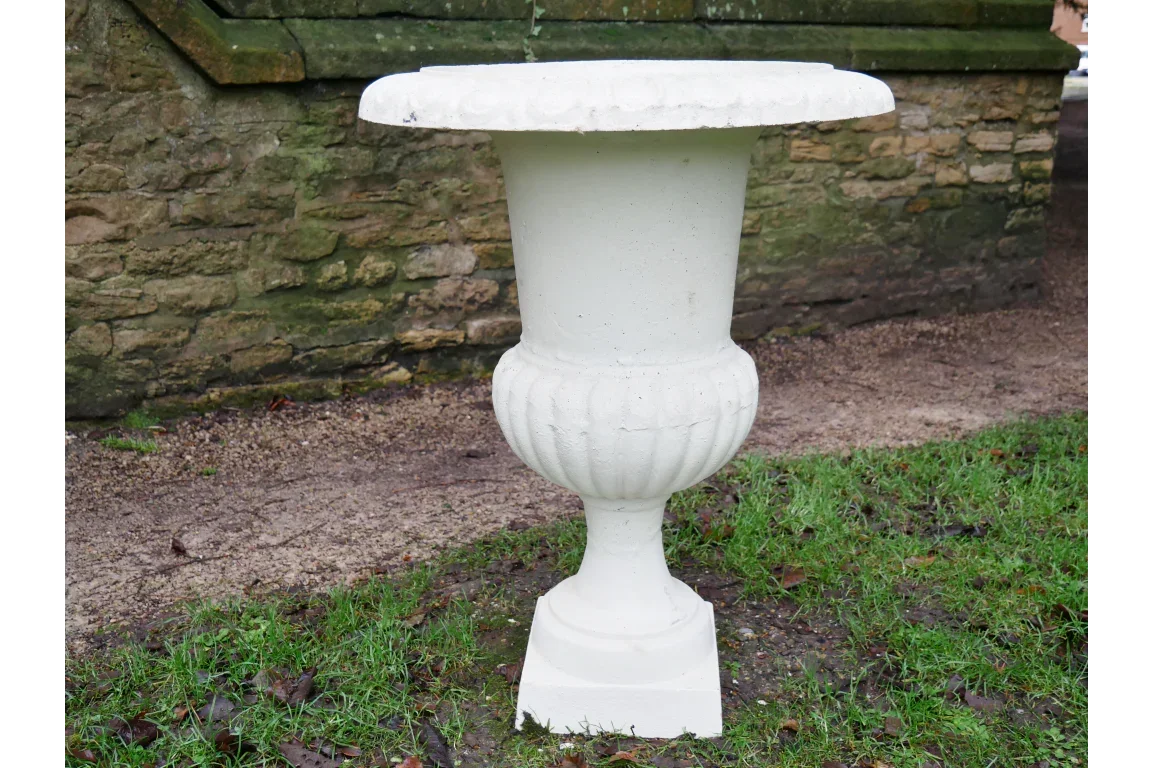 white stone garden planter urn on pedestal against stone wall outdoors