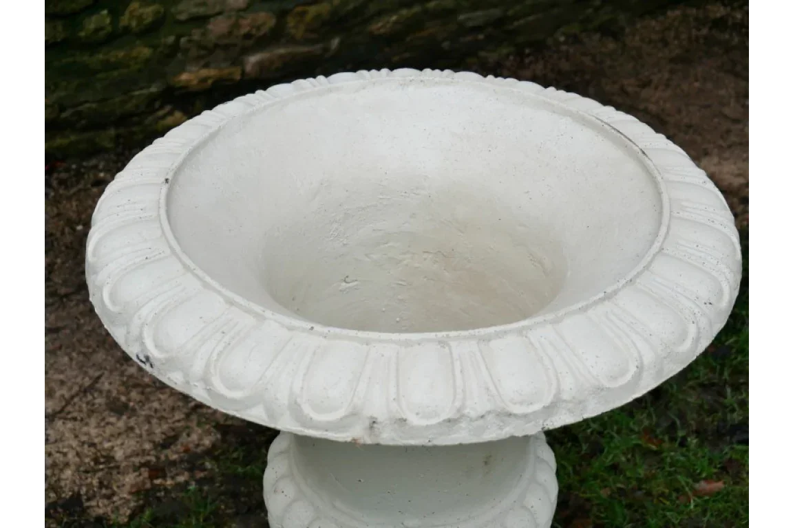 White stone garden planter with decorative rim positioned on grass and soil outdoors