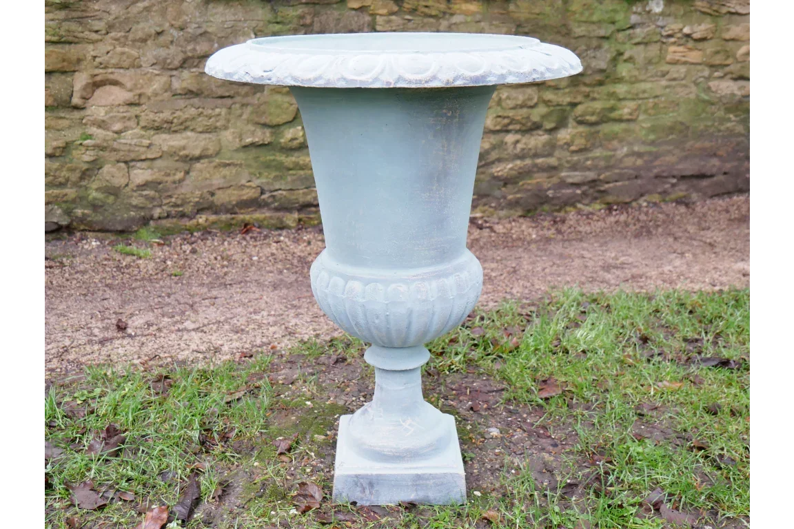 Classic stone garden planter urn with decorative rim and pedestal base on lawn