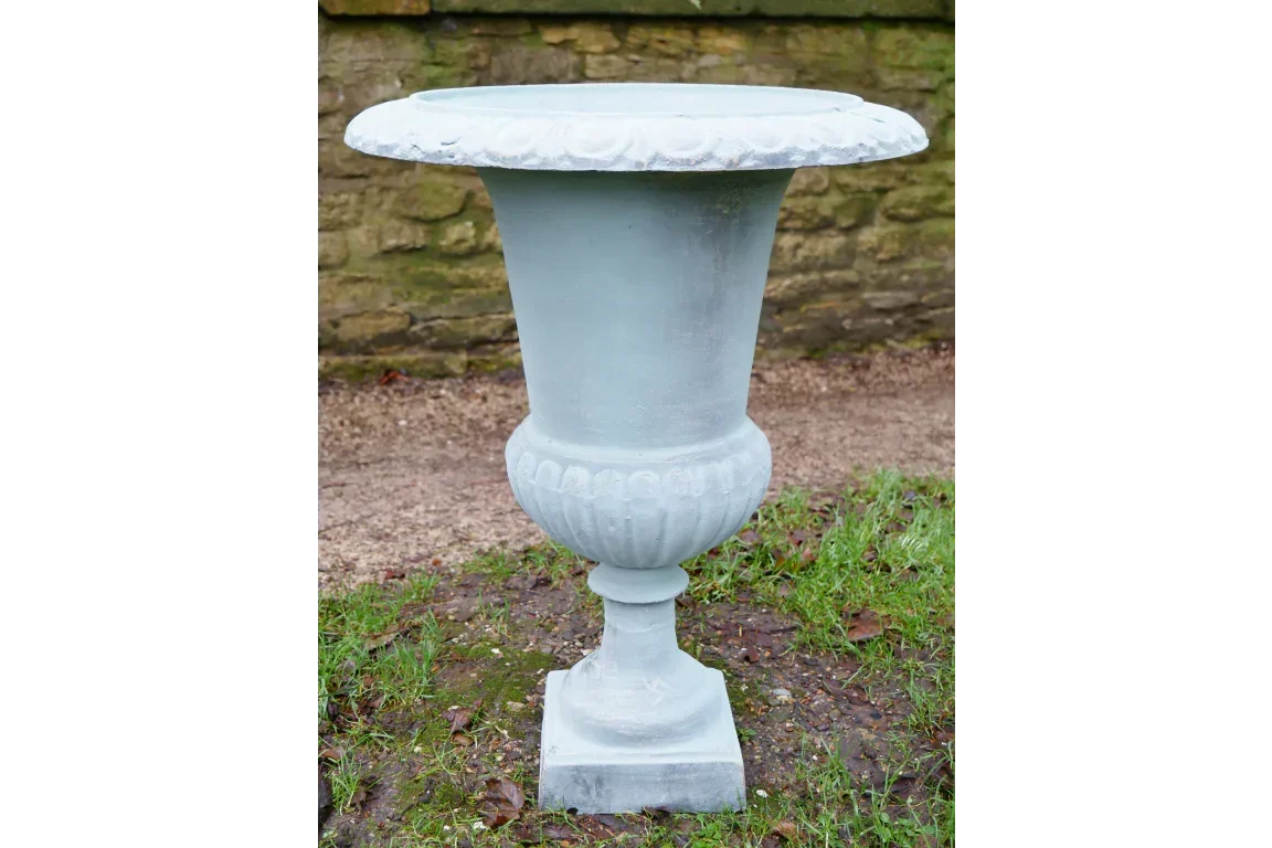 Stone garden planter urn with fluted design on pedestal base outdoors