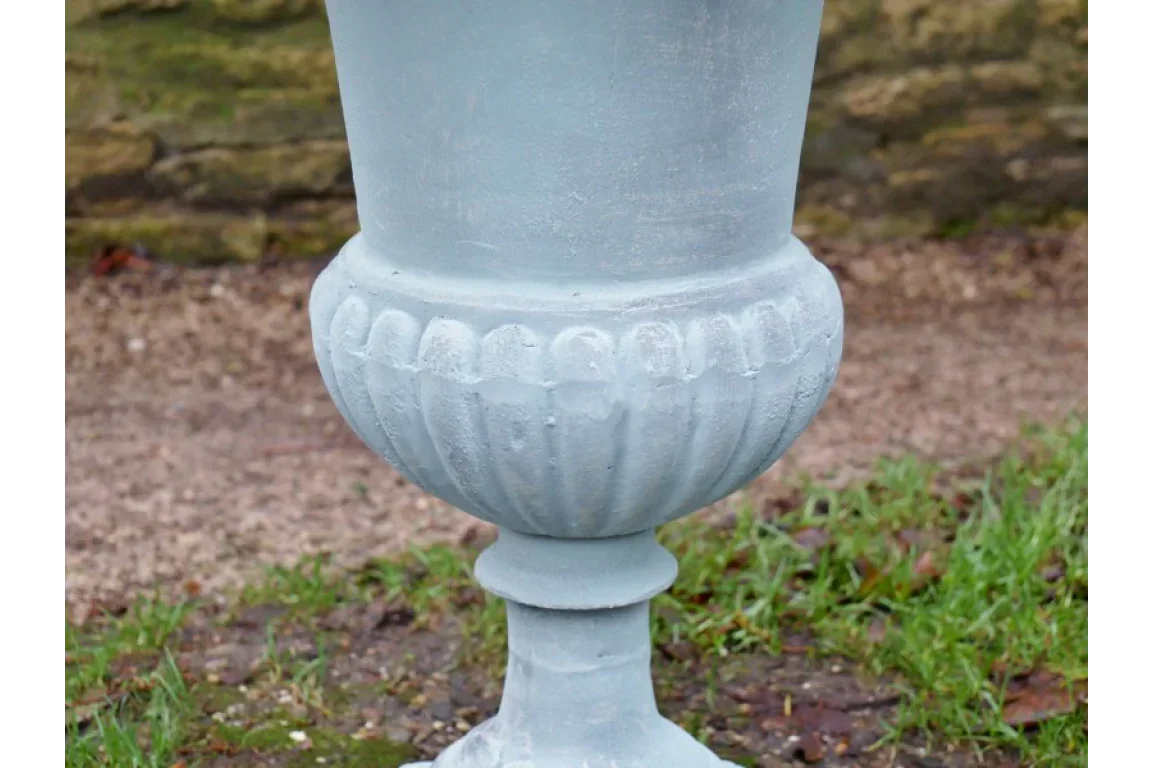 Light grey garden planter with decorative base on outdoor stone and grass surface
