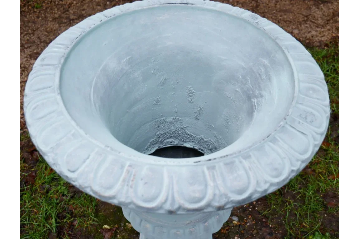White stone garden planter with ornate rim on outdoor grass and soil