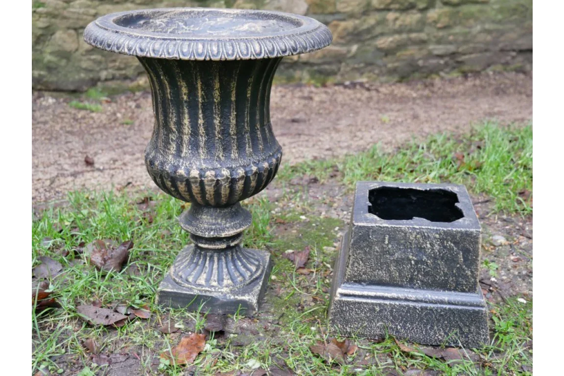 Black and gold garden urn planter with separate square base on outdoor grass