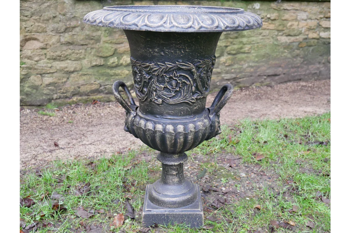 Black cast iron garden planter urn with floral detail and handles on lawn