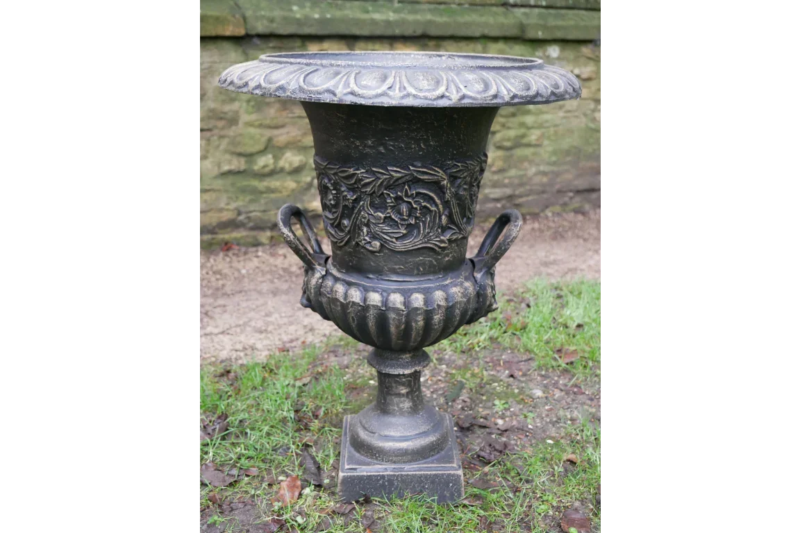 black cast iron garden urn planter with ornate detailing and handles on outdoor grass