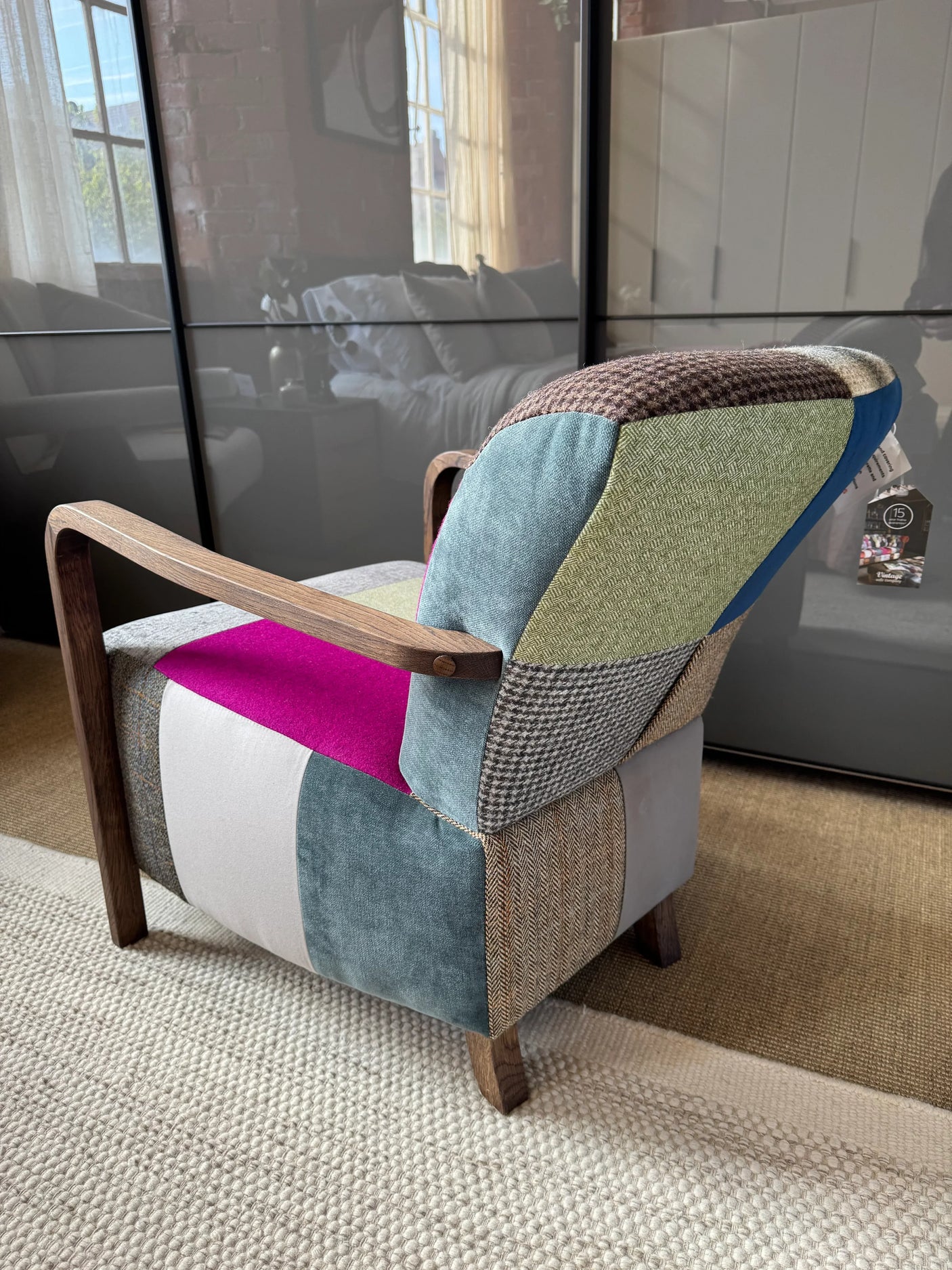Patchwork fabric accent chair with wooden arms on beige rug in bright living room